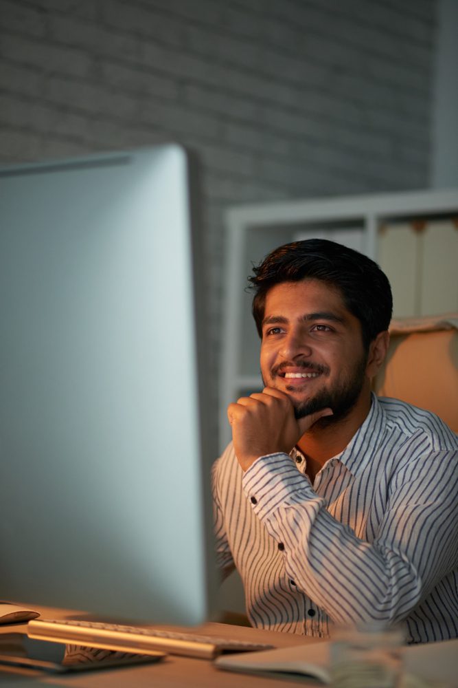 Business owner smiling at his desktop computer screen