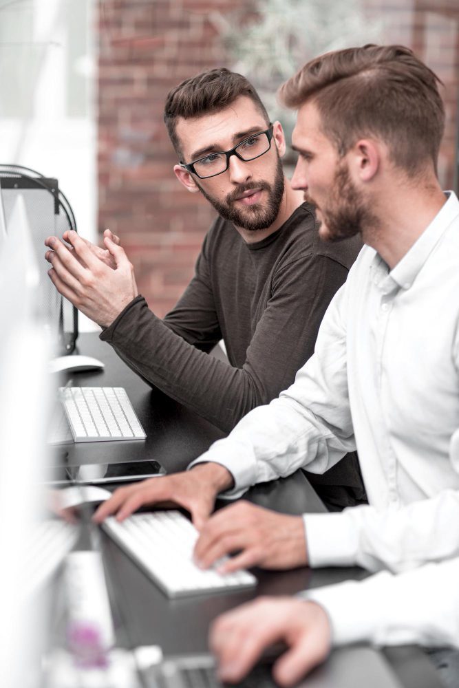 Web designer explaining a website build to a client at a computer