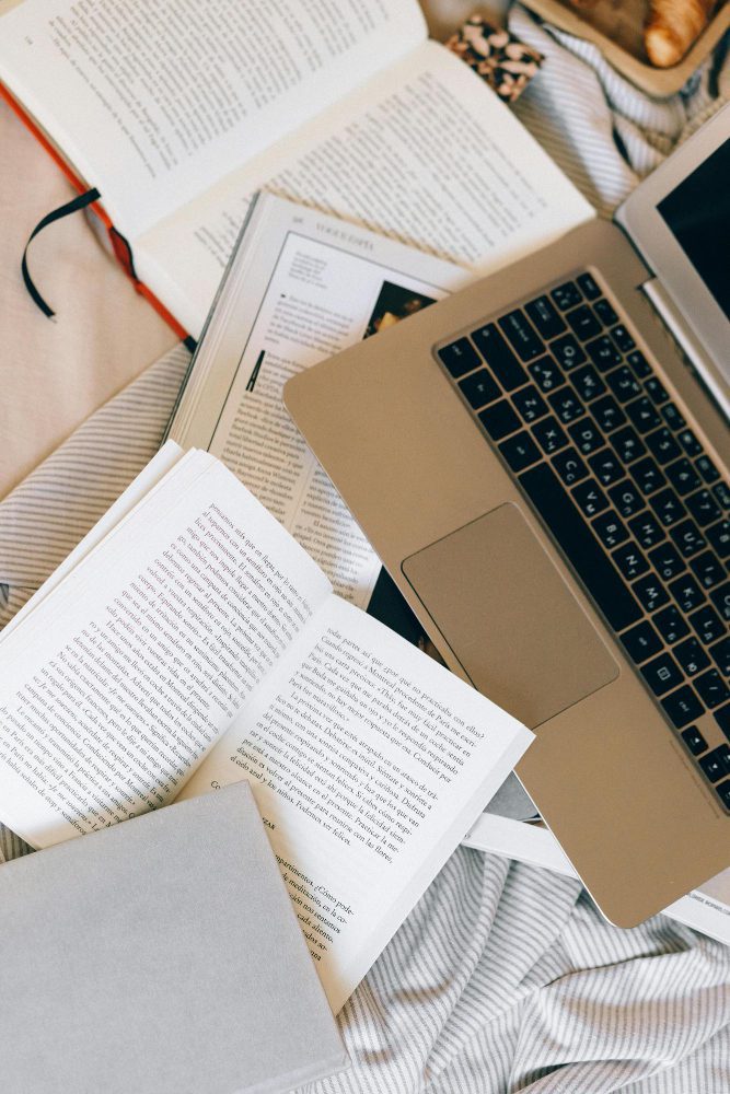 Website Design for Authors - overhead view of a laptop surrounded by open books and research notes
