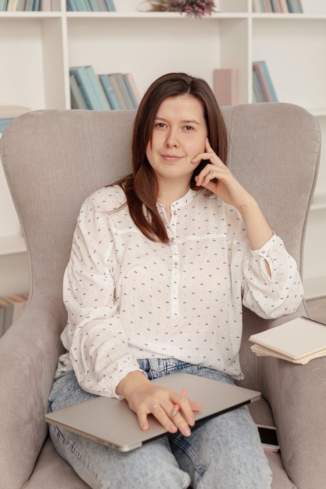 Woman taking a phone call while sitting in an armchair with a laptop