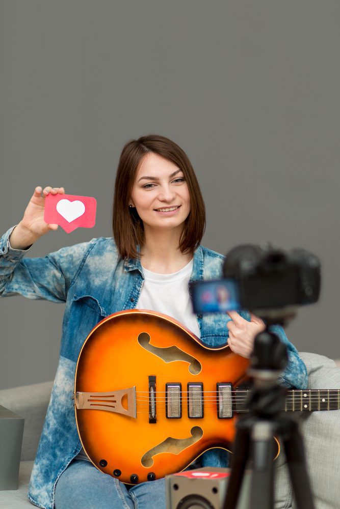 Musician with a guitar filming social media content and holding a like icon