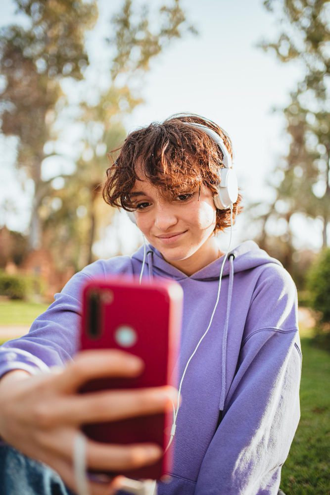 Young person filming a selfie video on a phone outdoors