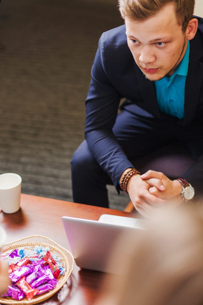 Man in a suit checking his phone at a meeting table