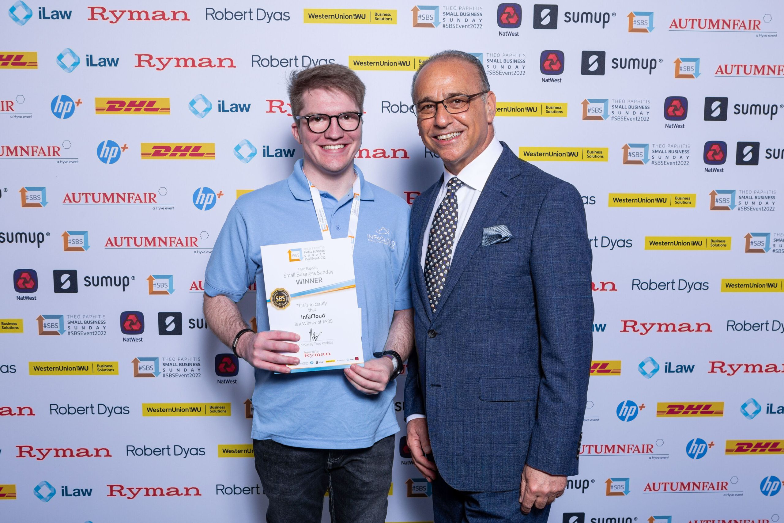 Two men displaying an award, standing together with smiles in a professional environment.