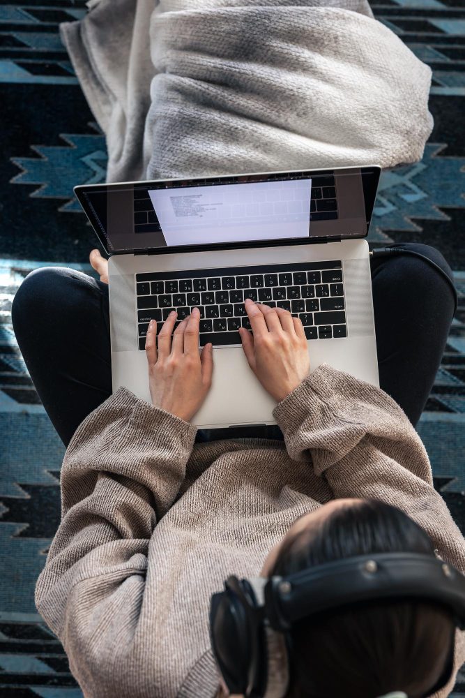 Website design - overhead view of someone using a laptop on their lap with headphones nearby