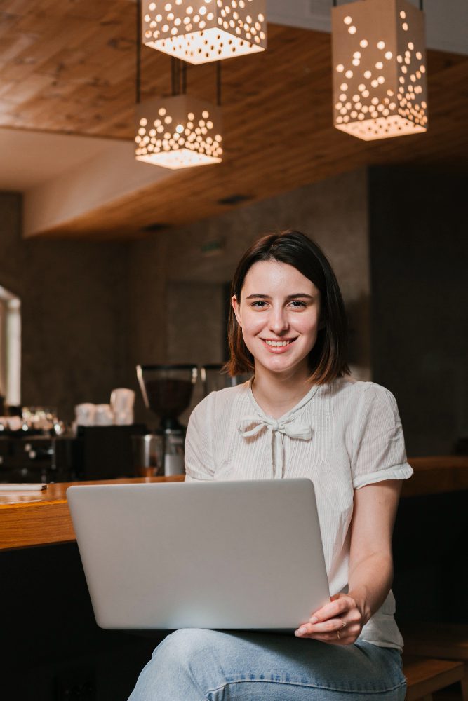 Website design - woman with a laptop on her knee in a warmly lit cafe