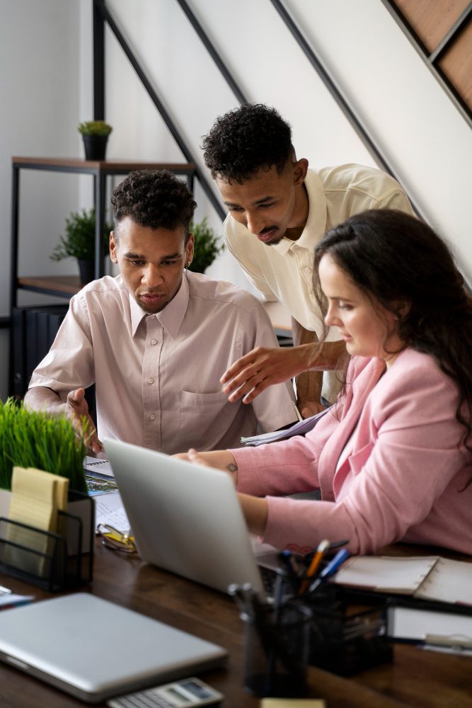 Website design - three colleagues gathered around a laptop at a desk