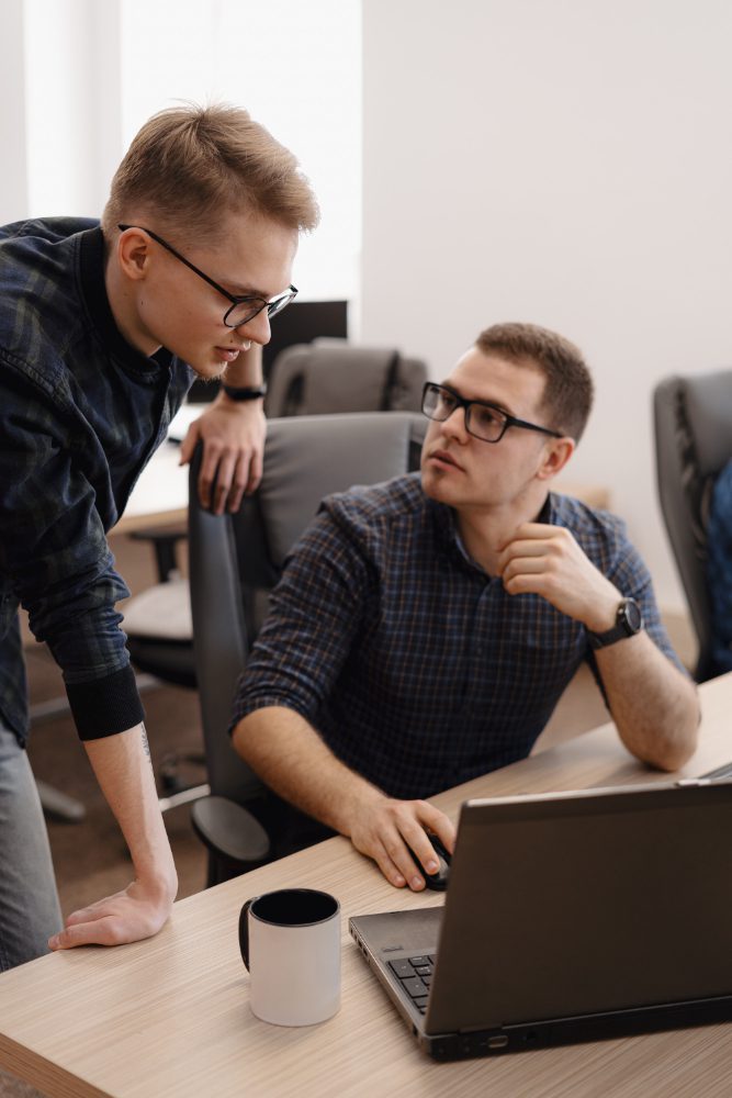 Website design - two colleagues talking over a laptop at a desk