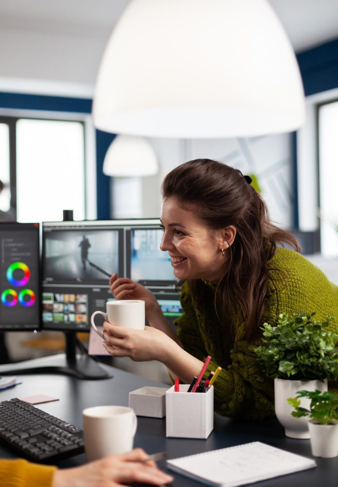 Website design - designer with a mug at a colour-grading desk with dual screens