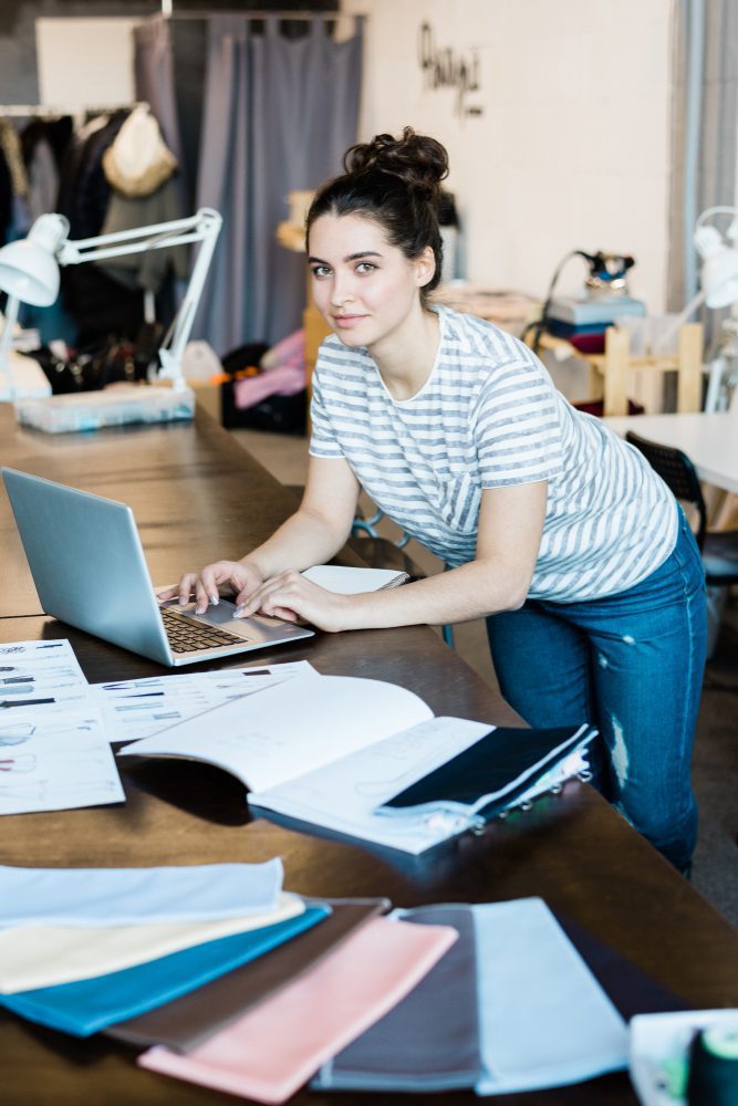 Website design - woman working at a laptop surrounded by paperwork