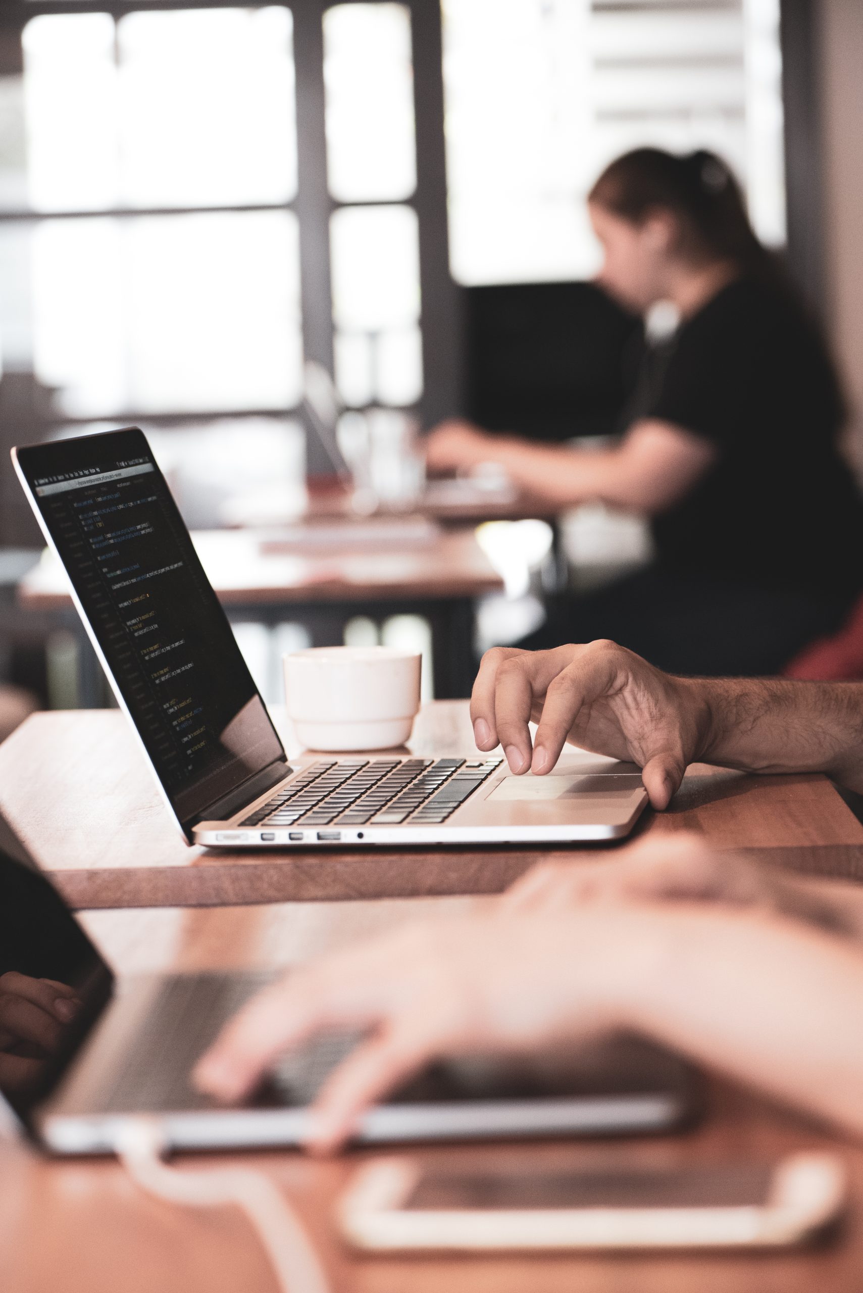 Website design - hands on a laptop in a busy shared workspace