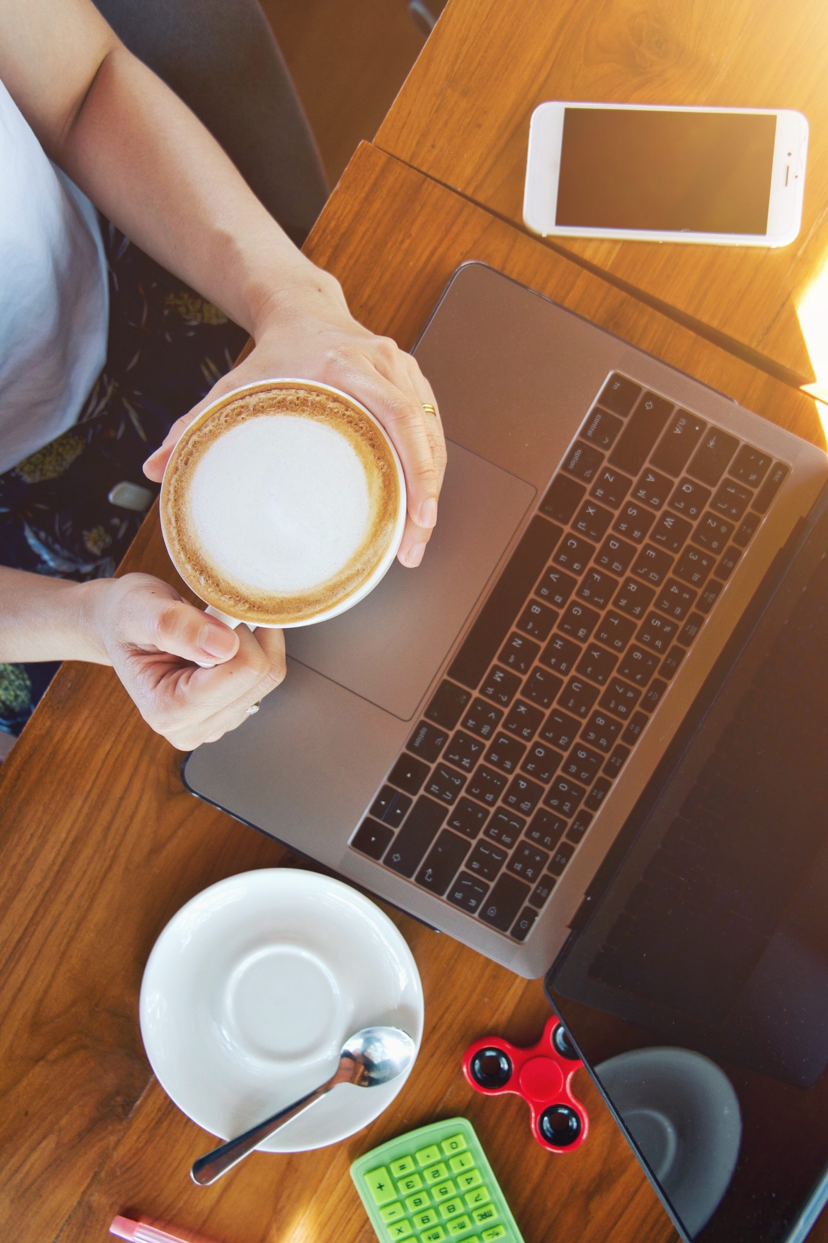 Website design - overhead view of hands holding a coffee beside a laptop and phone