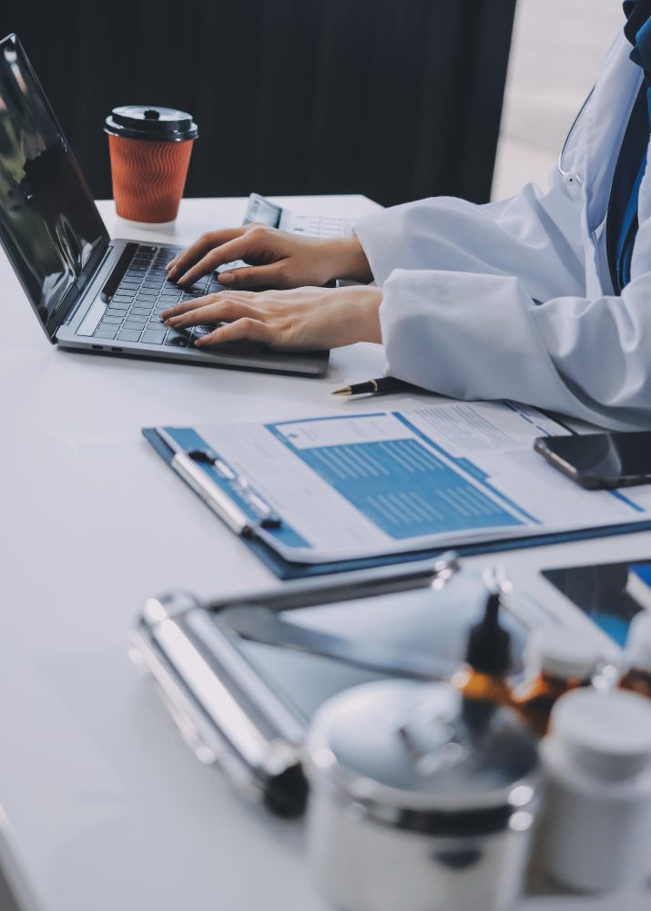 Medical website design in Newcastle - a doctor working at a laptop beside patient notes