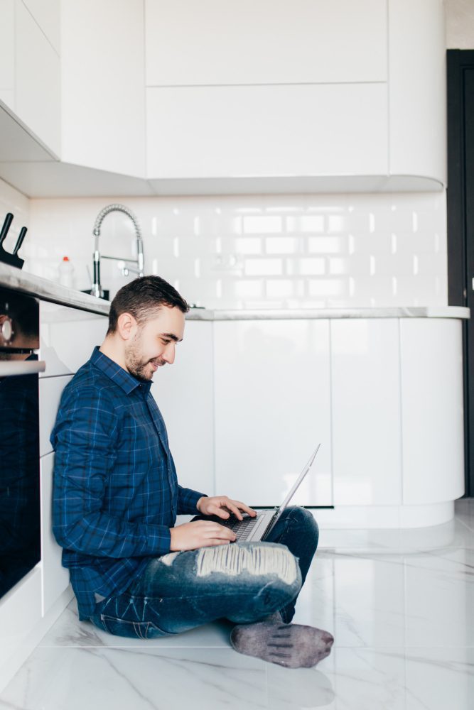 Website design for Seaham plumbers - a plumber using a laptop on a kitchen floor between jobs