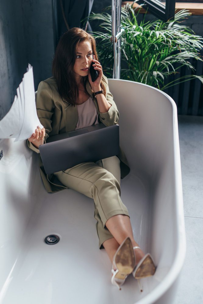 Website design - woman taking a call with a laptop while sitting in a bath tub