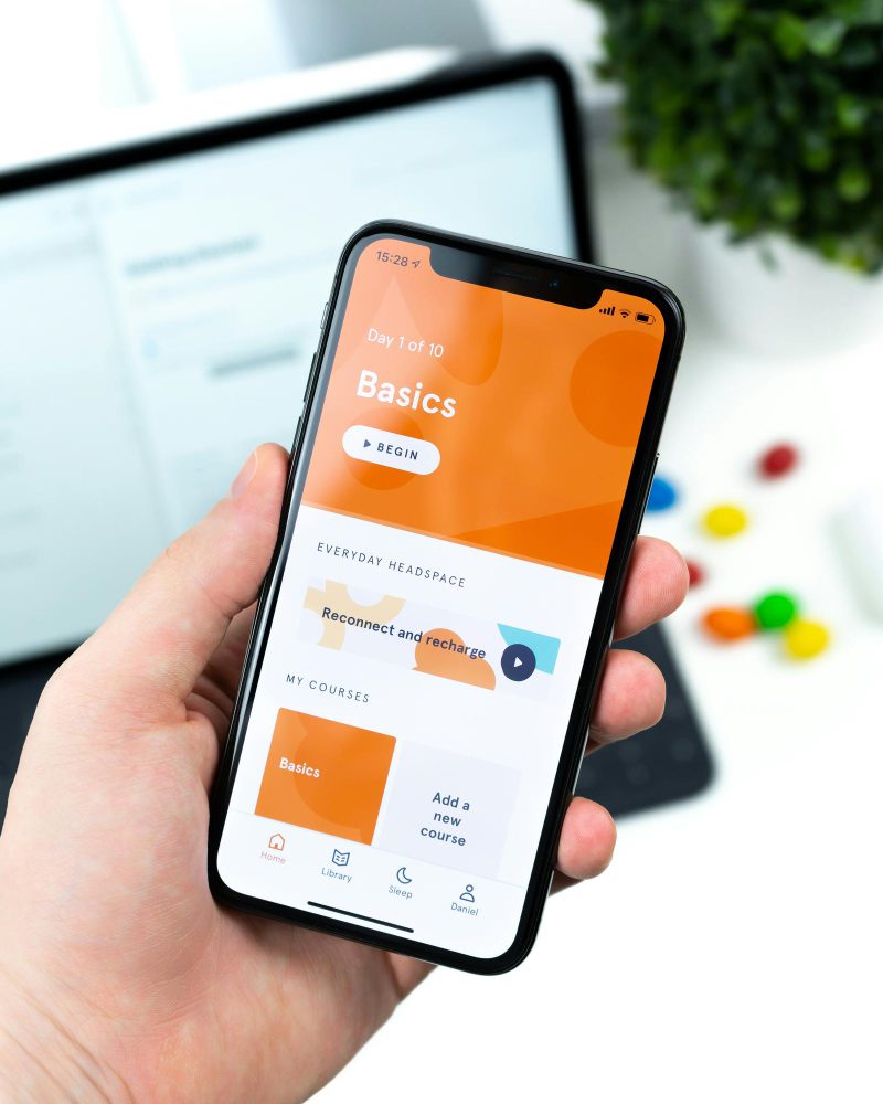 Mobile website design in Newcastle - a hand holding a phone showing an orange app interface