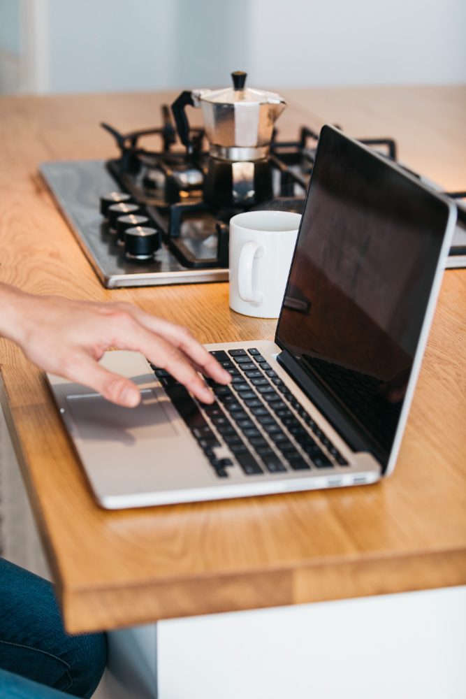 Website design - hands on a laptop at a kitchen table beside a moka pot