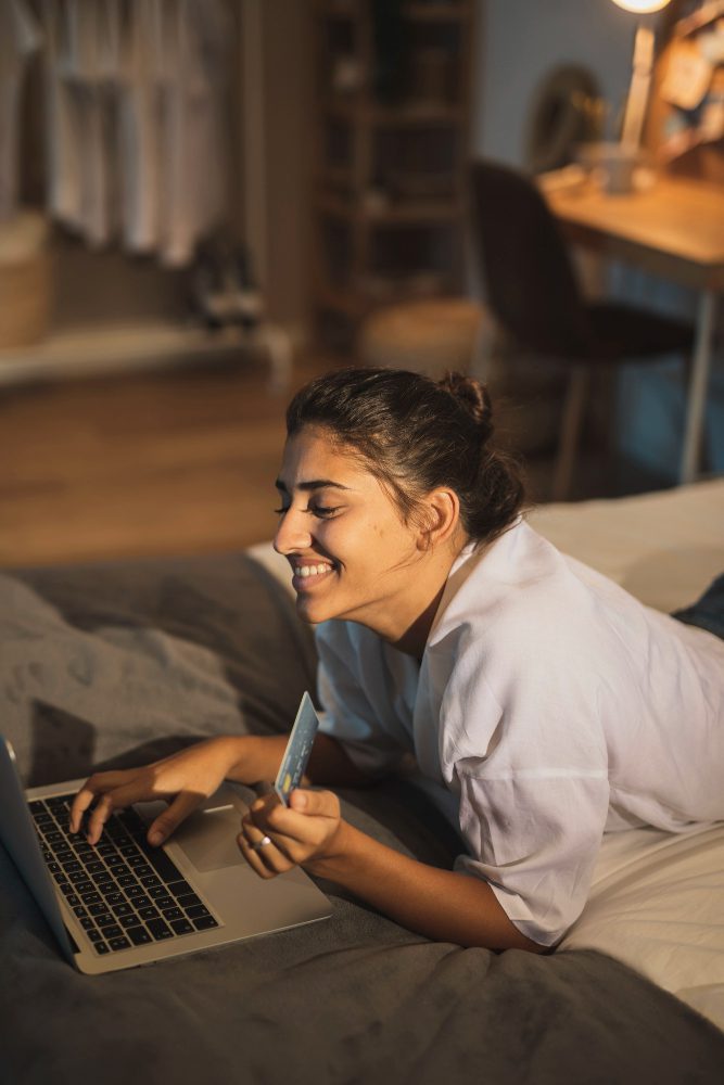 Website design - woman using a laptop while lying on a bed