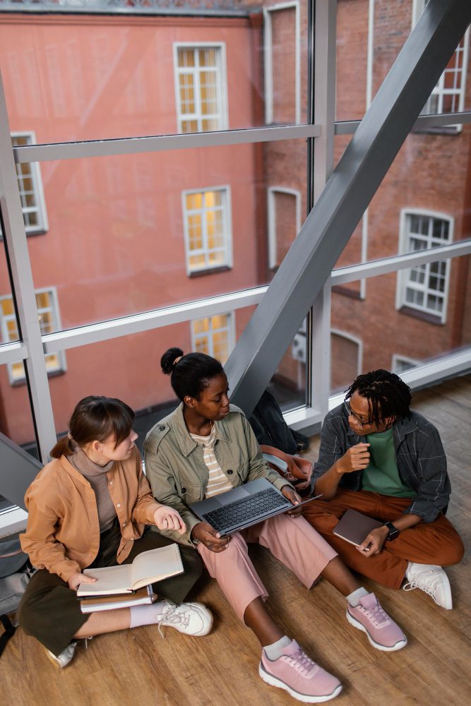 Website design - three students working together on a laptop on the floor