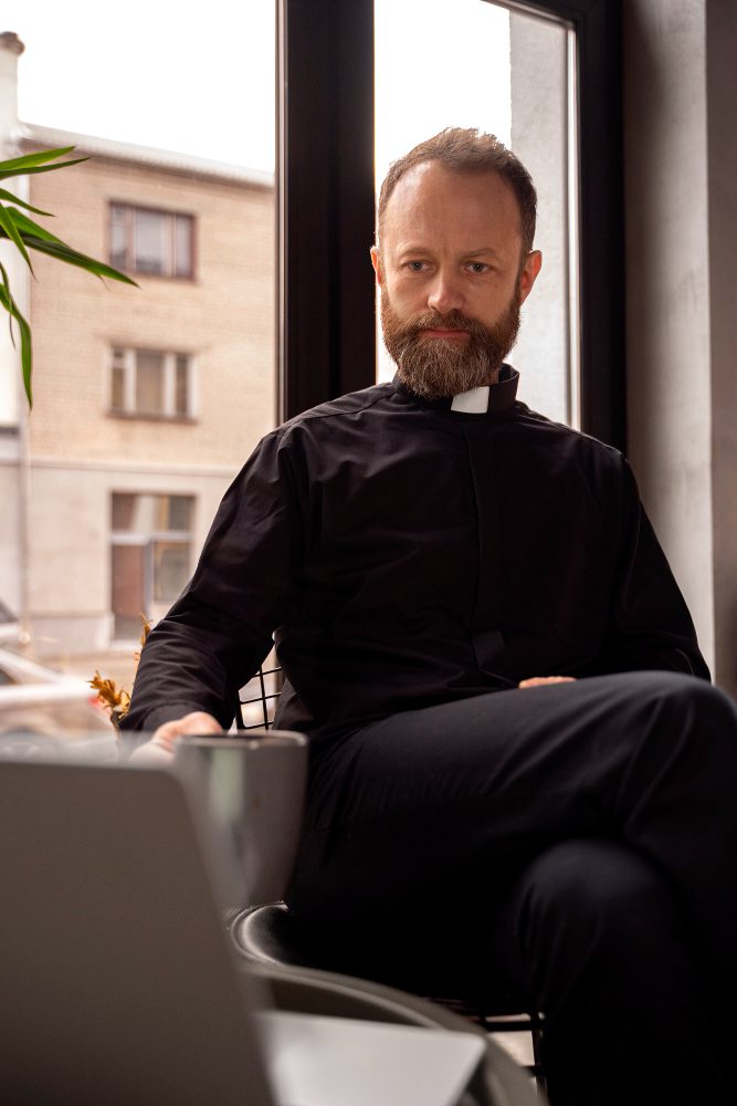 Website design - clergy member in a clerical collar using a laptop