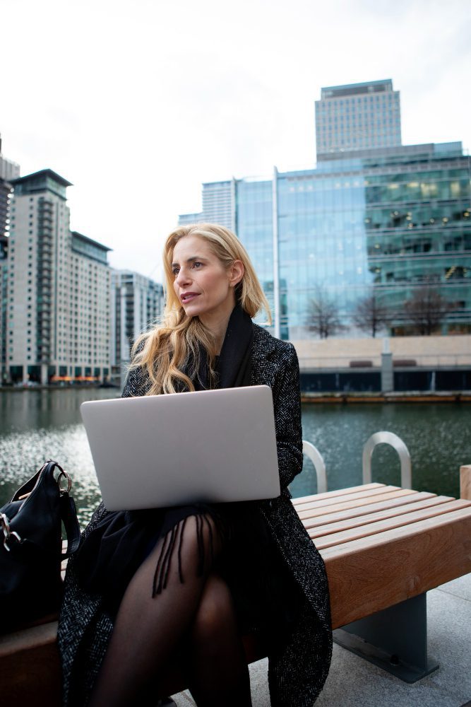 Website design - woman working on a laptop on a bench by the waterfront