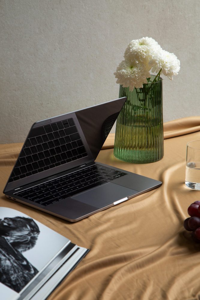 Website design - laptop on draped fabric beside a vase of white flowers