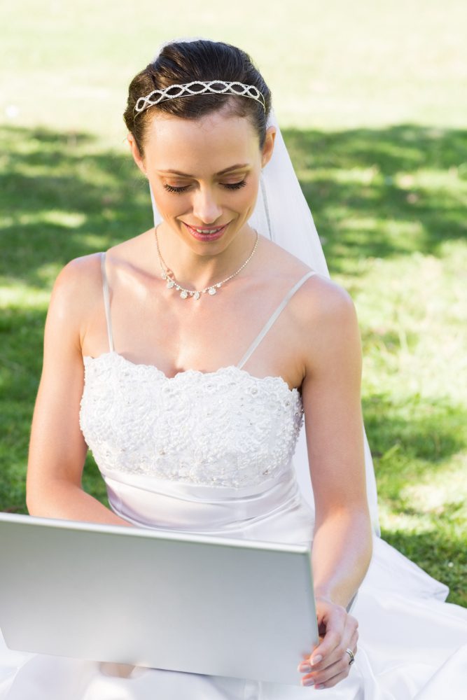 Website design - bride in a white dress using a laptop outdoors
