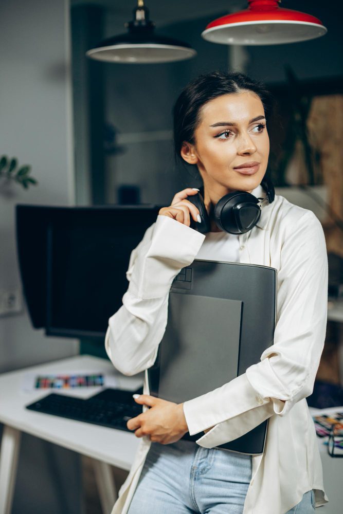 Website design - woman holding a laptop with headphones round her neck