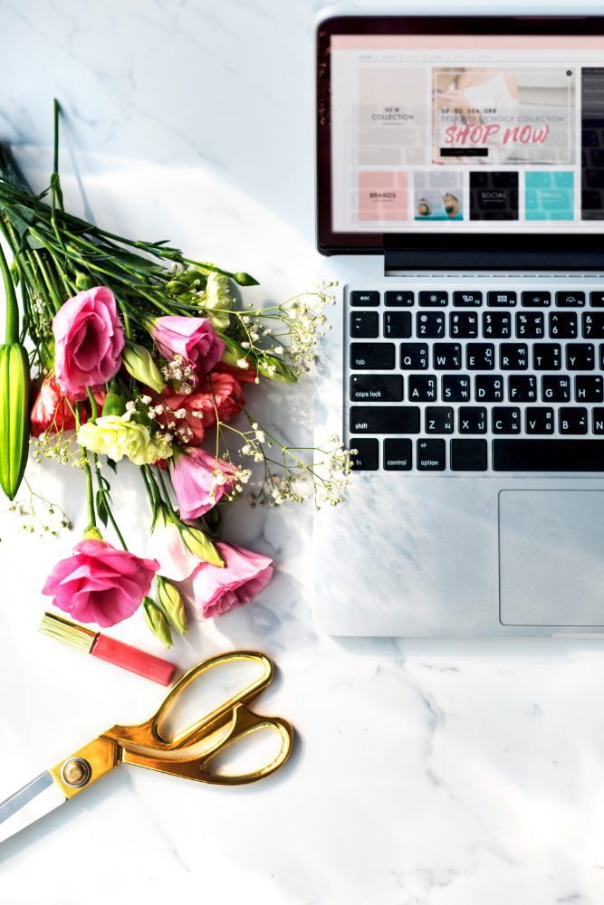 Website design - laptop surrounded by fresh flowers, scissors and ribbon