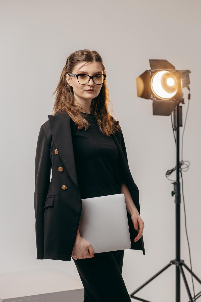 Website design - woman holding a laptop beside a studio light