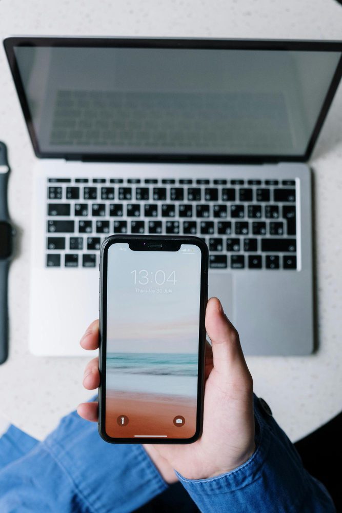 Website design - hands holding a phone beside an open laptop