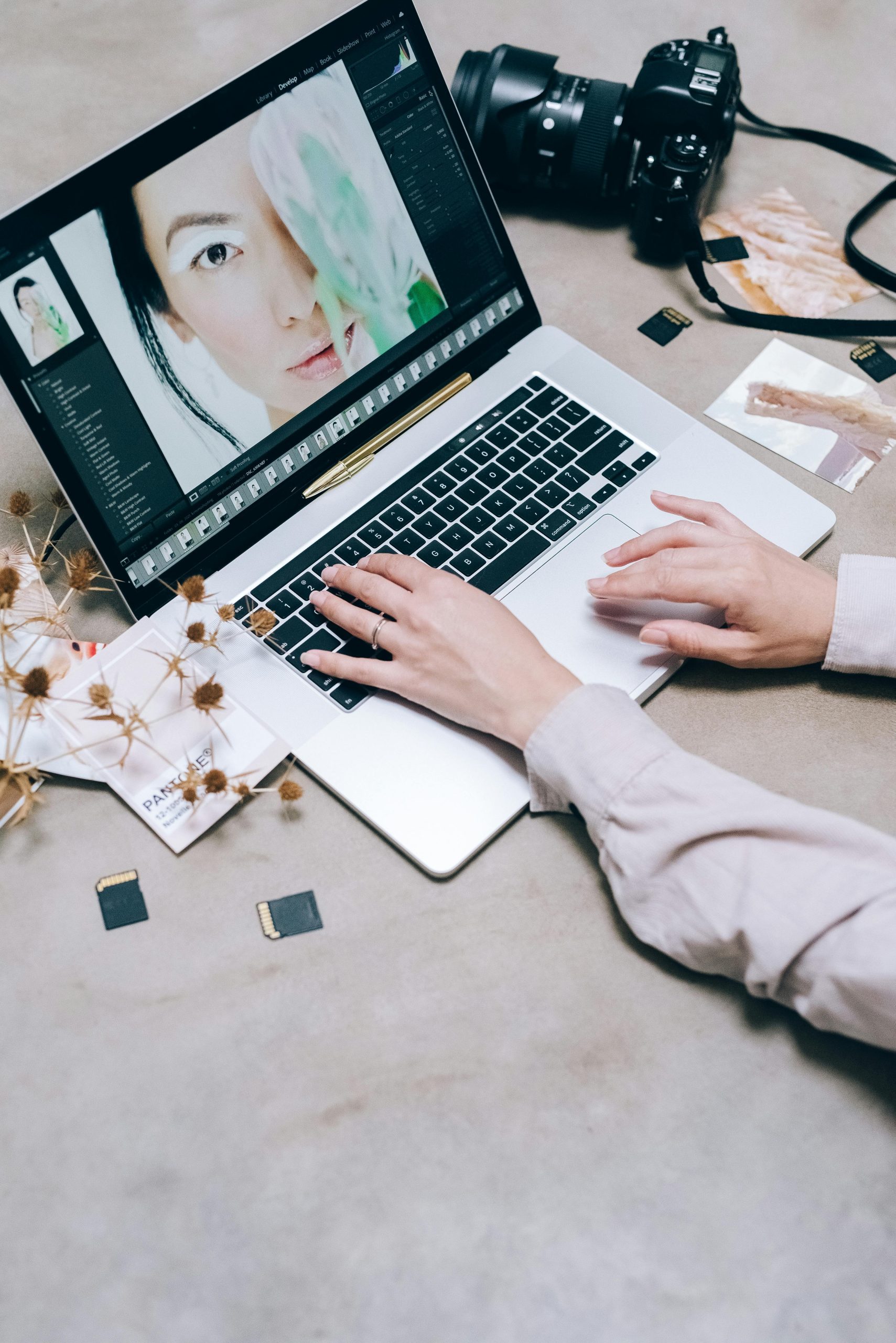 Social media - hands editing a portrait on a laptop beside a camera