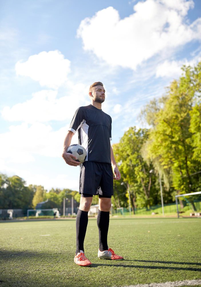 Website design - footballer standing on the pitch holding a match ball