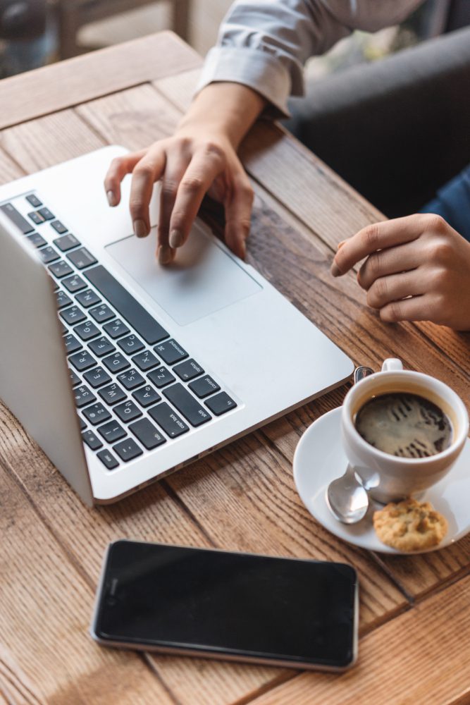 Affordable website design in Hartlepool - hands typing on a laptop beside a coffee and a phone