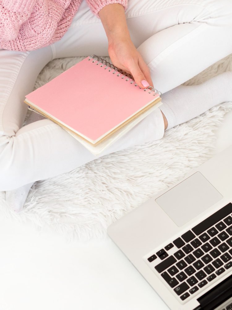 Website design - woman with a pink notebook and a laptop on a bed