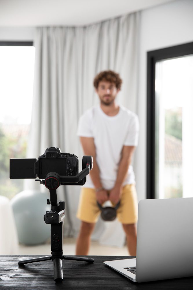 Social media - man recording video with a camera on a tripod at home