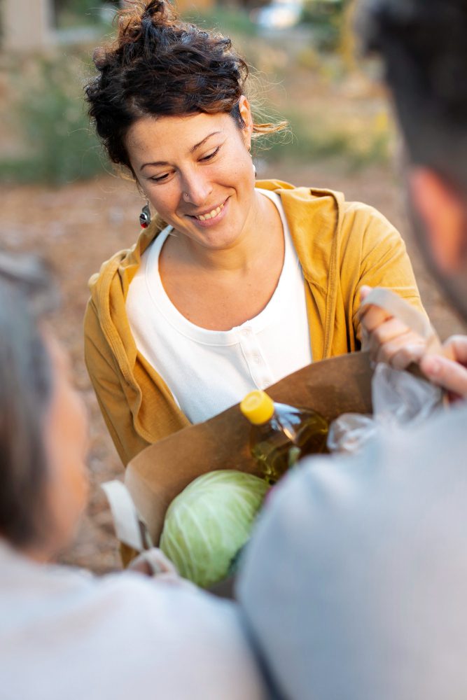 Website design - volunteer smiling while handing over a bag of food donations