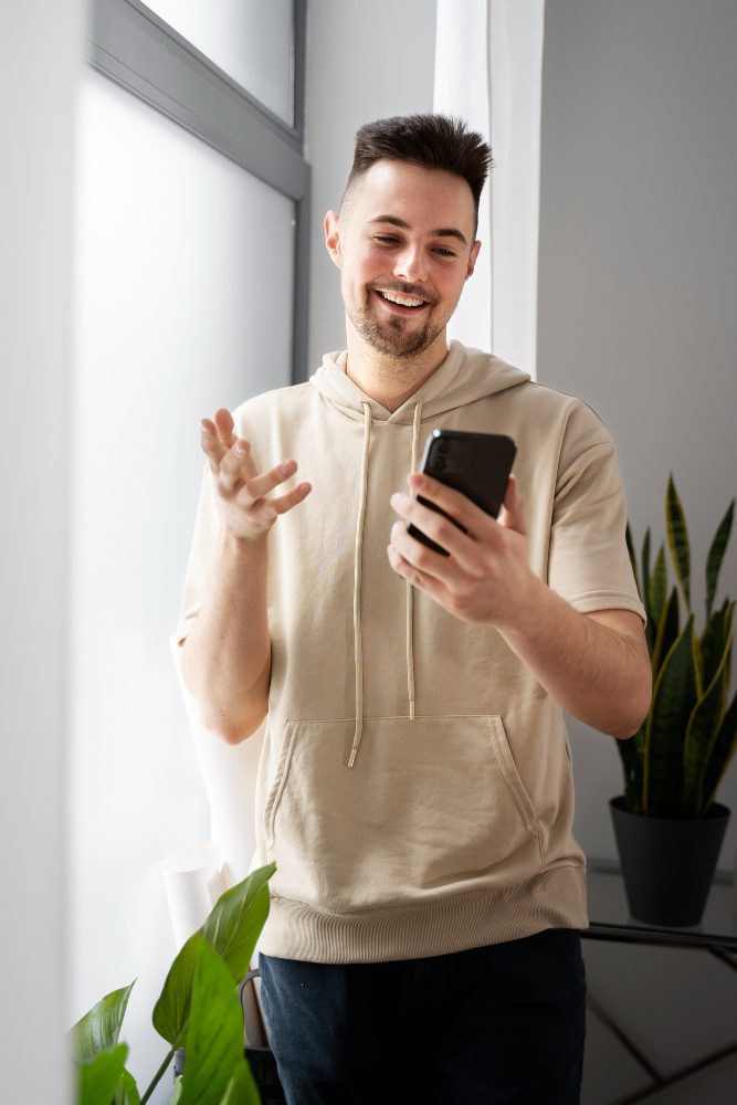 Website design - man smiling at his phone in a bright room