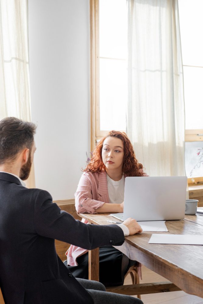 Website design - two people talking across a table with a laptop