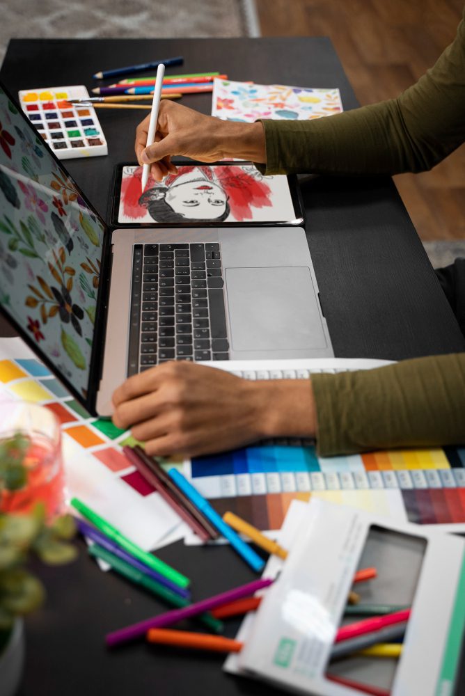 Website designers for artists in Newcastle - an artist painting with watercolours beside a laptop