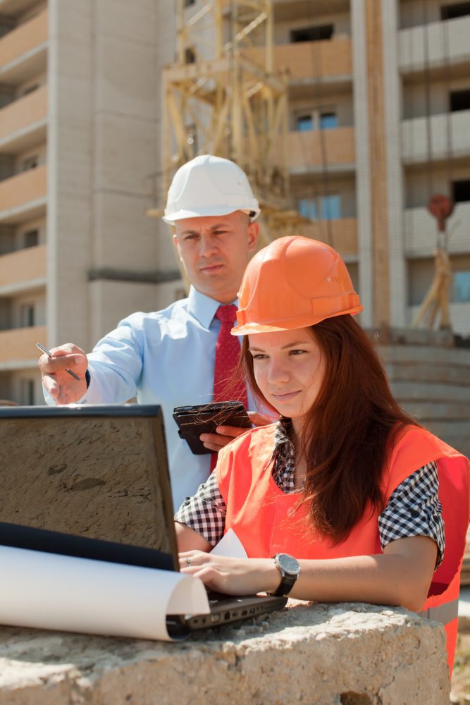 Website design - two people in hard hats using a laptop on a construction site
