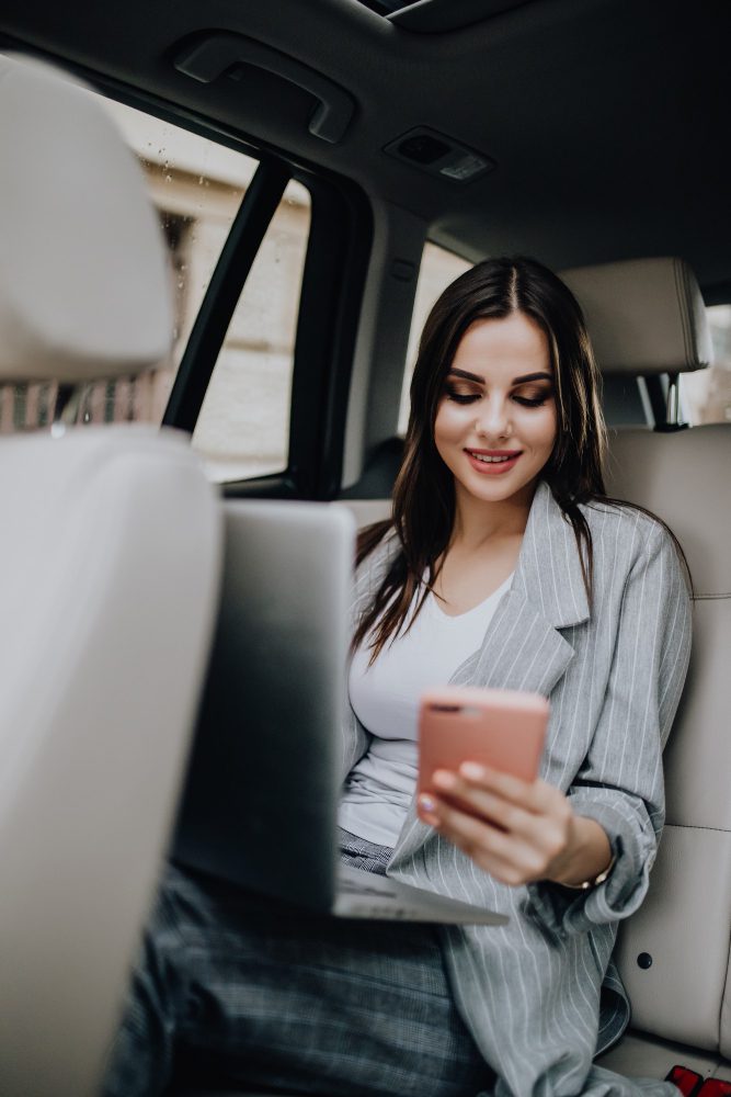 Website design - woman using a phone in the back seat of a car