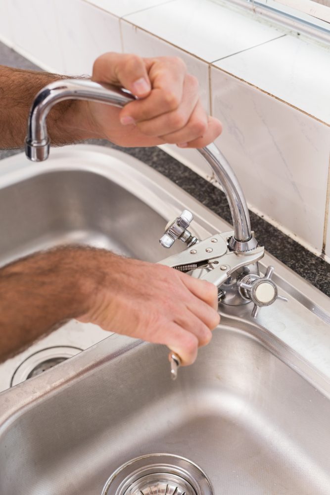 Trade website design in Doncaster - a plumber fitting a kitchen tap over a stainless steel sink
