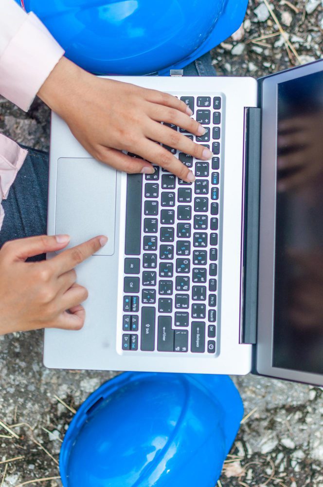 Website design - overhead view of hands on a laptop between two hard hats