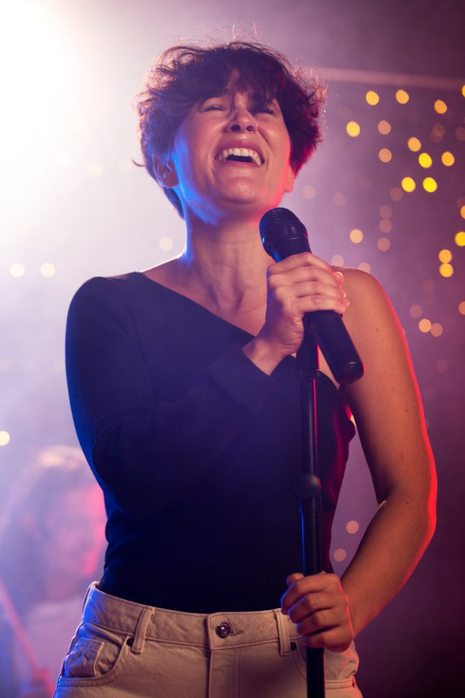 Social media - woman singing into a microphone on a lit stage