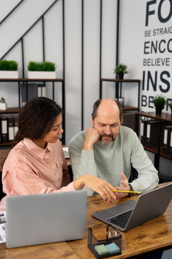 Website design - two colleagues working at laptops in a bright office
