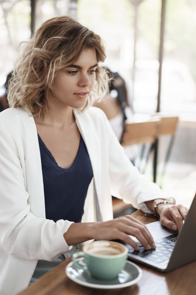 Website design - woman working at a laptop with a coffee in a cafe