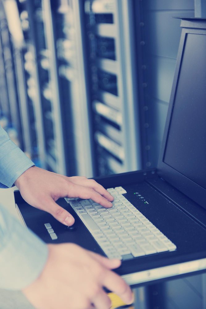 Web hosting - hands on a laptop in front of server racks
