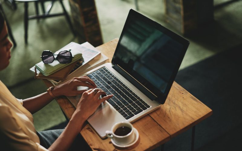 Website design - hands typing on a laptop beside a coffee