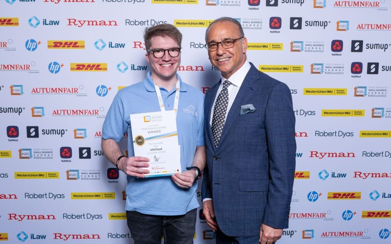 Two men displaying an award, standing together with smiles in a professional environment.